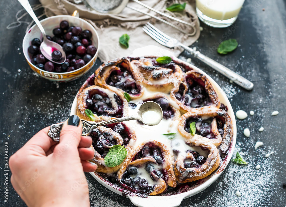 Blueberry buns with fresh mint and creamy sauce on dark backdrop