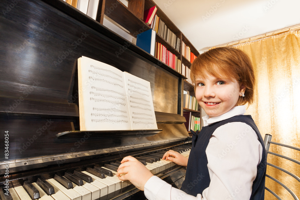 Smiling girl in school uniform playing the piano