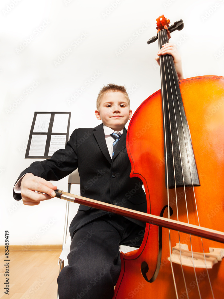 Portrait of boy playing cello sitting on the chair