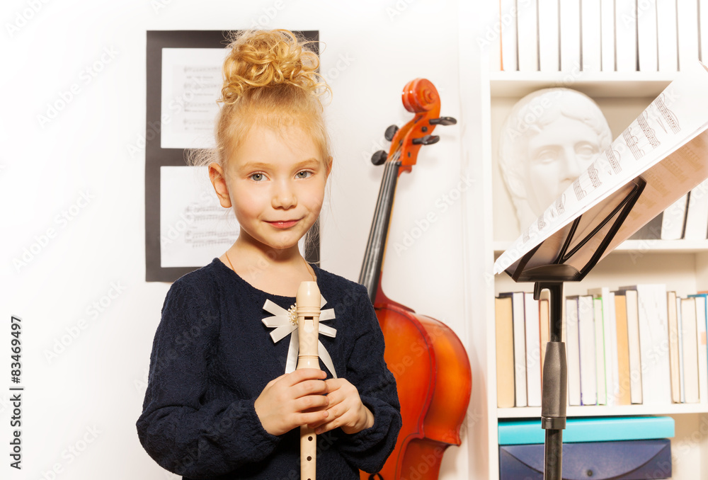 Cute blond girl with flute standing near cello