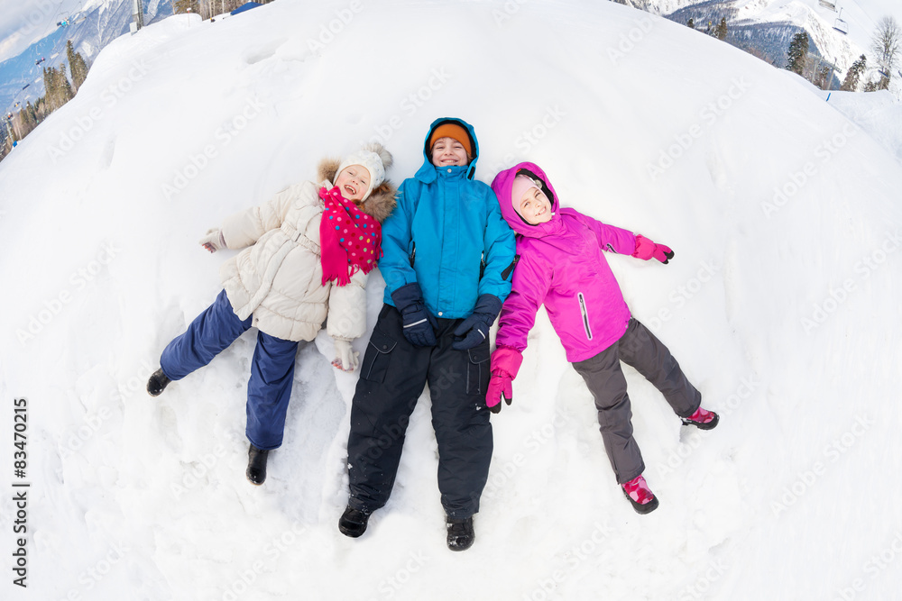 三个孩子双腿分开躺在雪地上