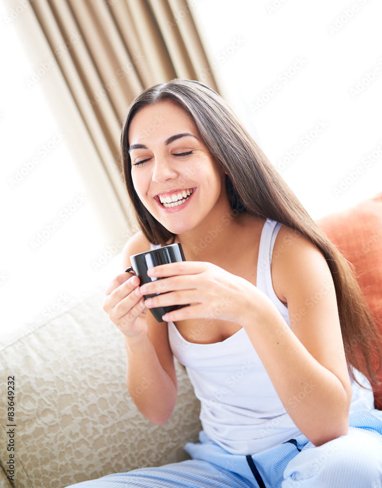 Woman smiling with eyes closed and holding warm drink