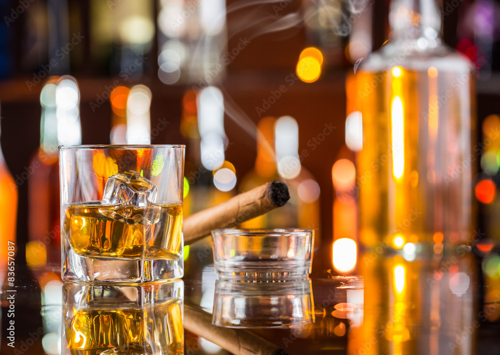 Whiskey drink with smoking cigar on bar