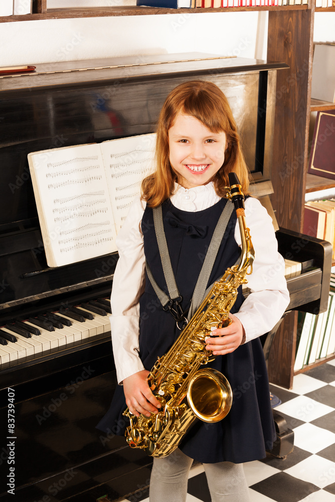 Smiling girl in school uniform with alto saxophone