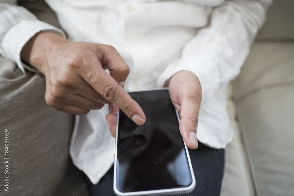 Men are using a mobile phone sitting on the sofa