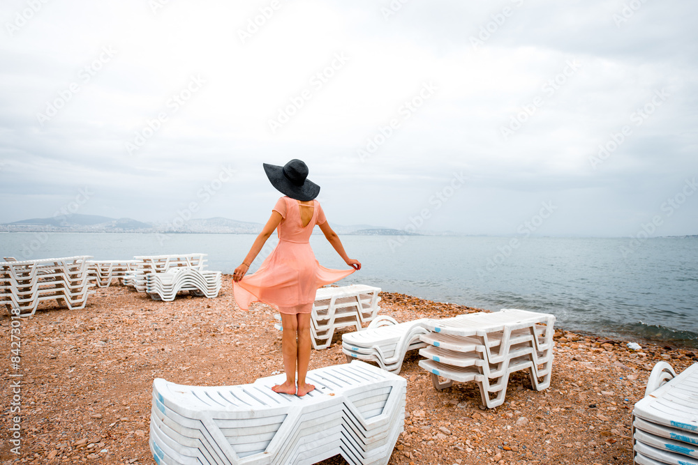 Woman on the deserted beach with many sunbeds