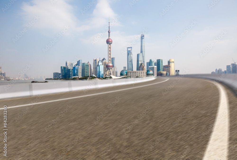 The fuzzy Asphalt road in front of the modern city， in Shanghai，china。