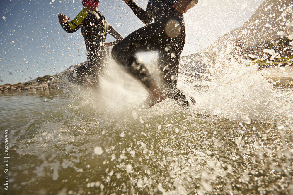 Triathlon participants running into the water for swim portion