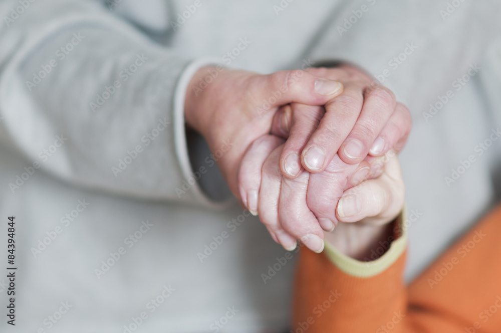 Frau haelt Hand von einer Seniorin