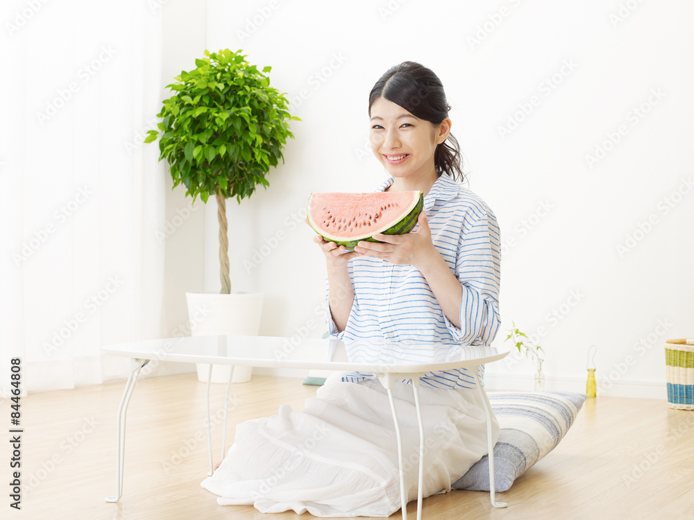 部屋で西瓜を食べる女性