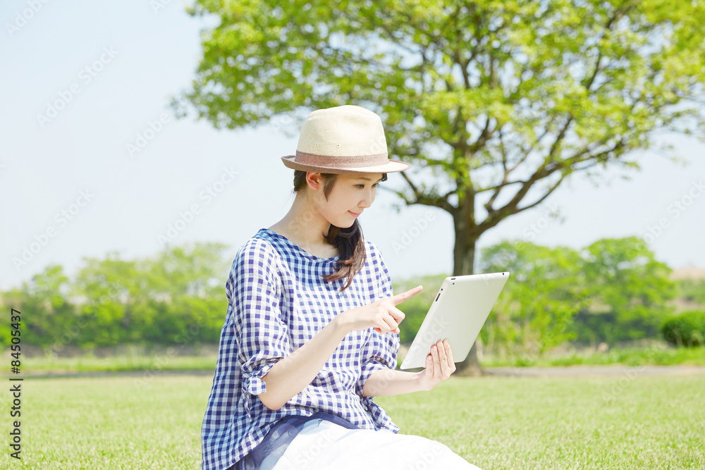 外でタブレットを使う女性