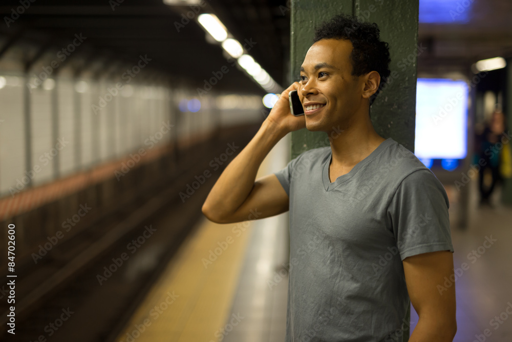 纽约市一名年轻的非裔亚裔男子晚上在地铁里打手机