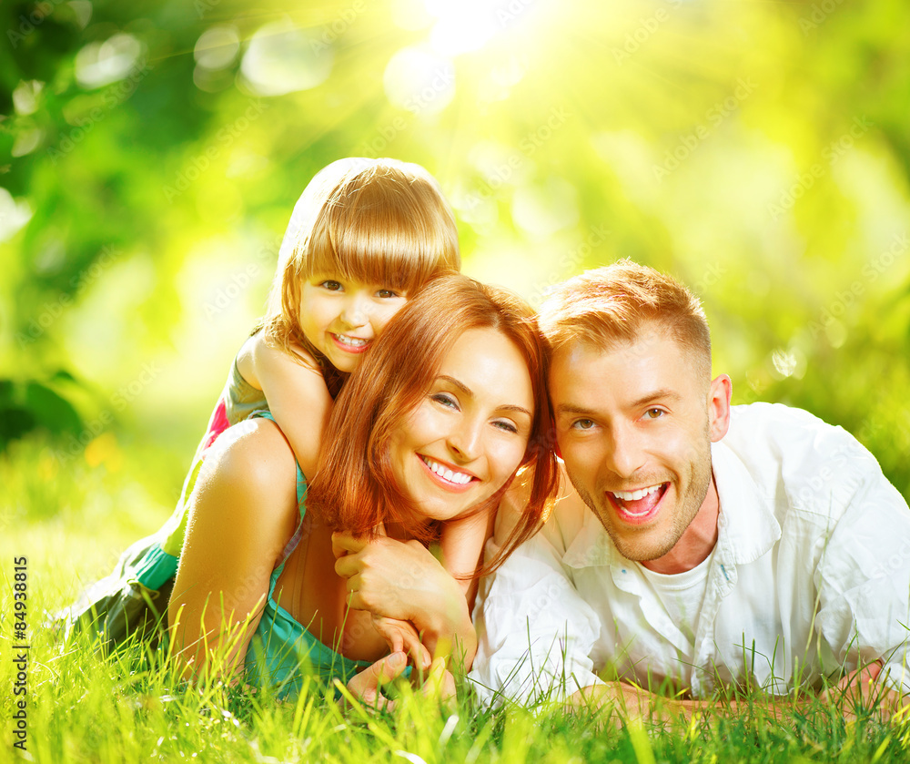 Happy joyful young family playing together in summer park