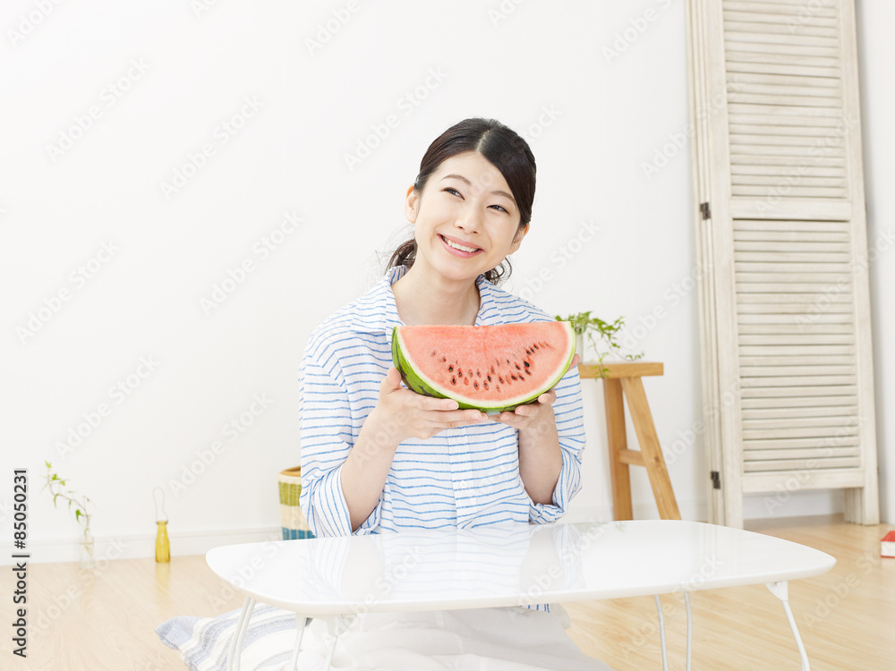 部屋で西瓜を食べる女性