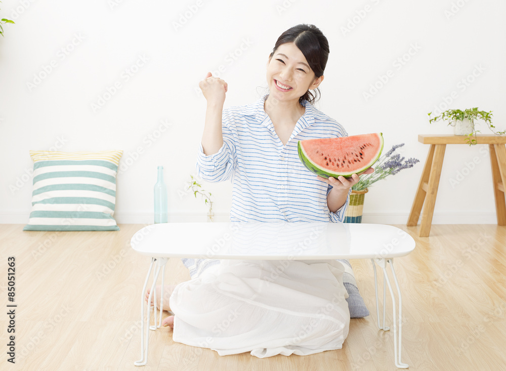 部屋で西瓜を食べる女性　ガッツポーズ