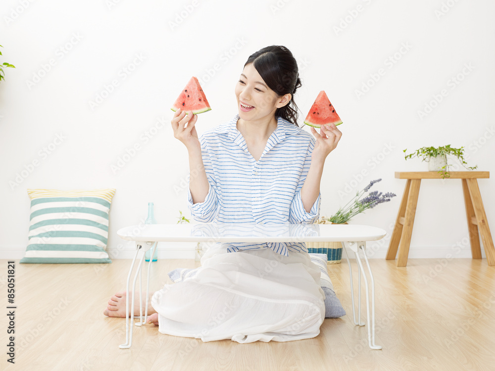 部屋で西瓜を食べる女性