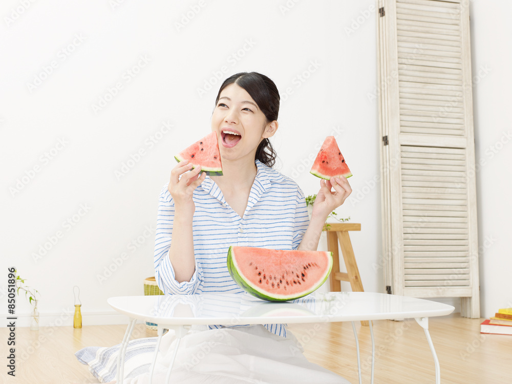 部屋で西瓜を食べる女性