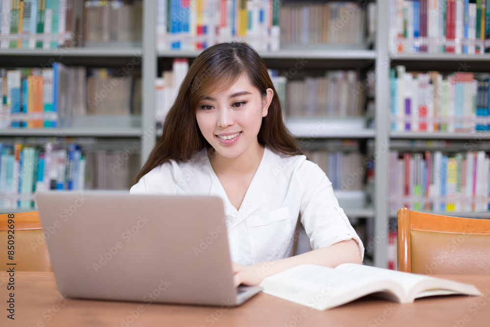 Beautiful asian female student using laptop for study in library