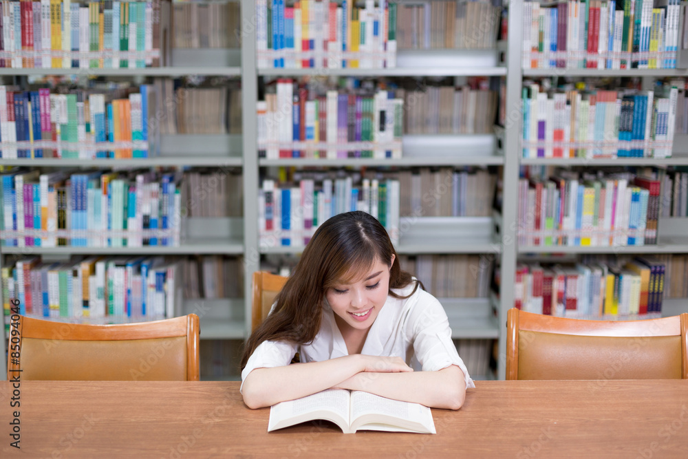 漂亮的亚洲女学生在图书馆看书