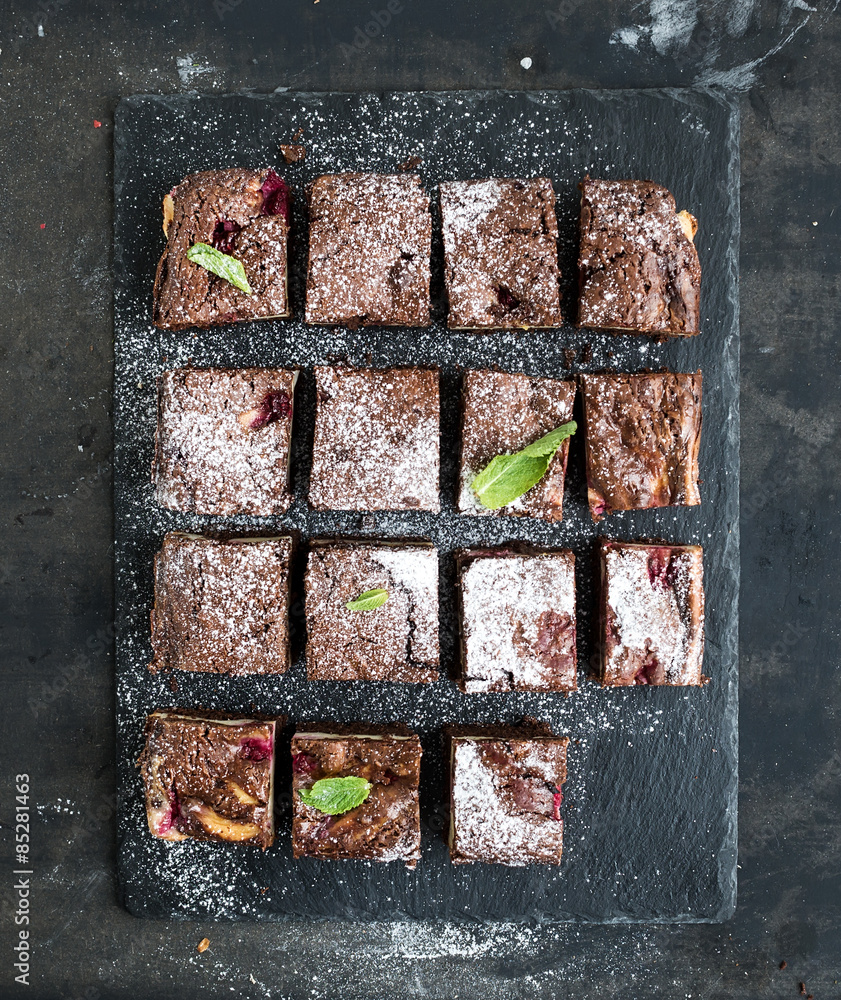 Chocolate and raspberry brownie squares on black stone board