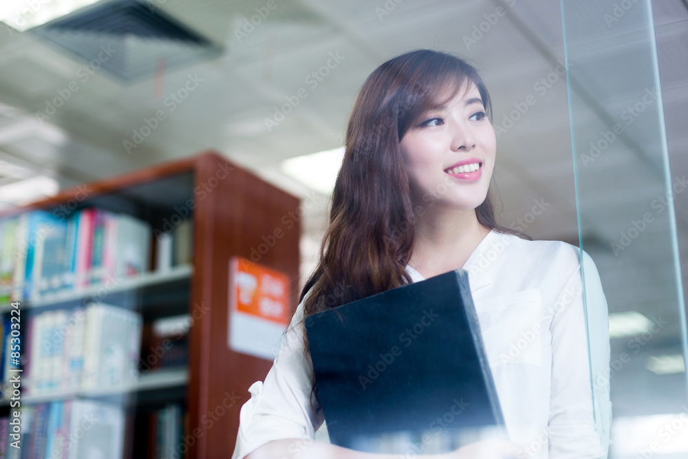 Asian female student looking book in library