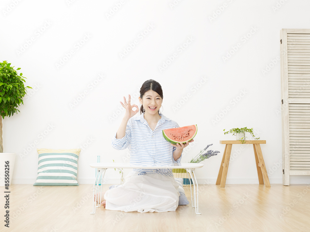 部屋で西瓜を食べる女性　OKサイン