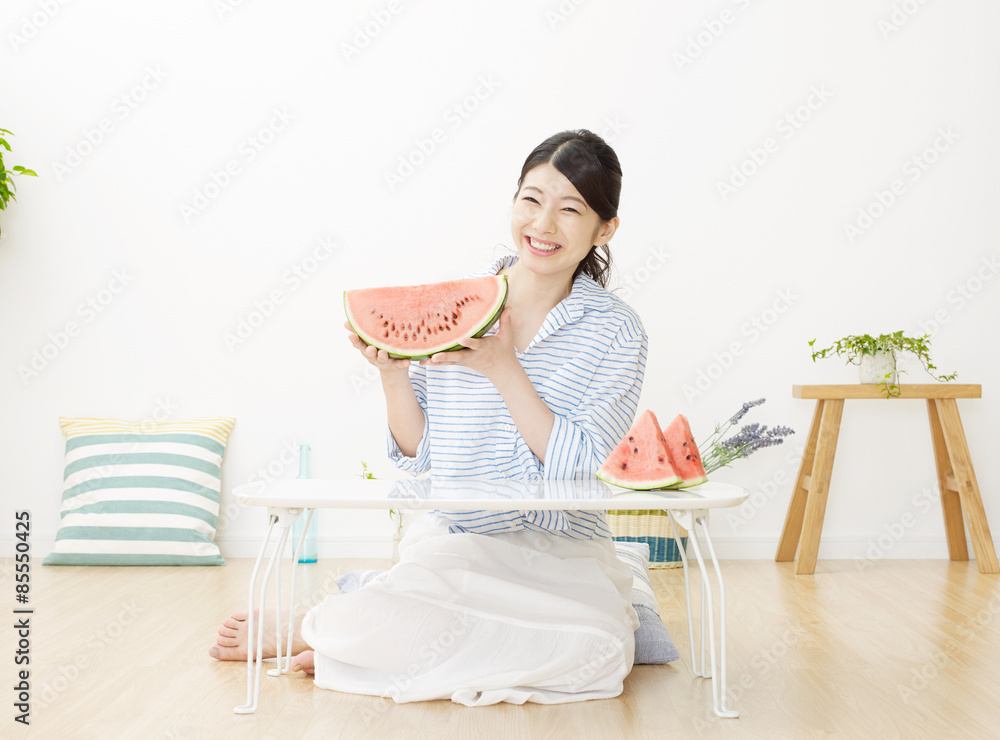 部屋で西瓜を食べる女性