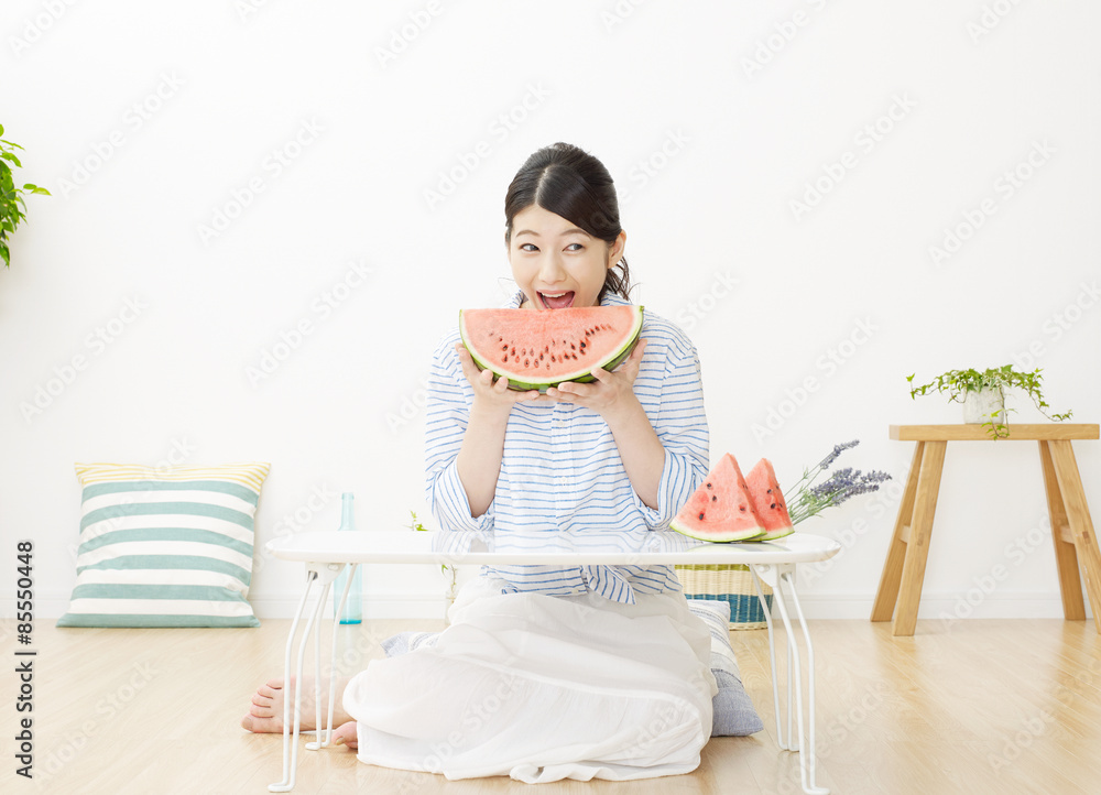 部屋で西瓜を食べる女性