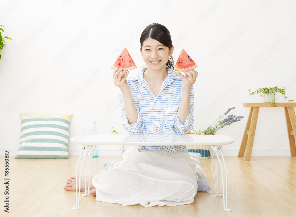 部屋で西瓜を食べる女性