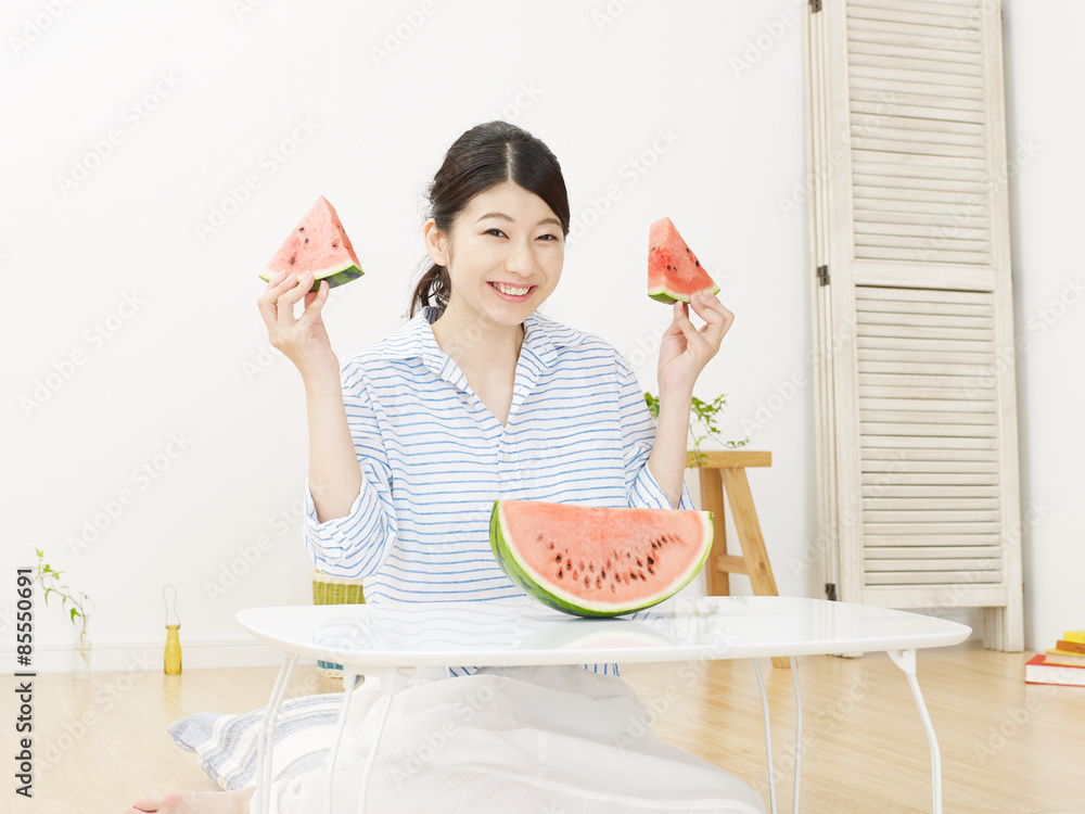 部屋で西瓜を食べる女性