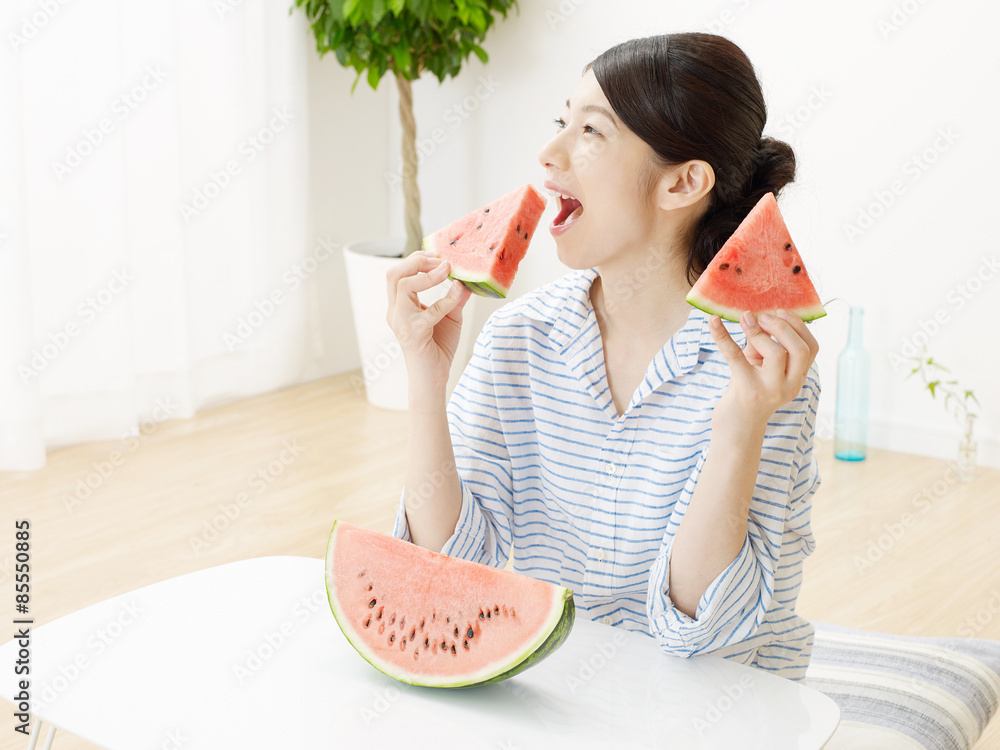 部屋で西瓜を食べる女性