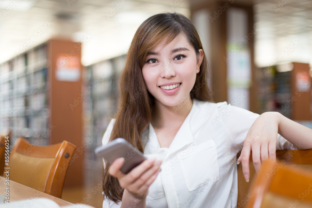 亚洲美女女学生在图书馆使用手机