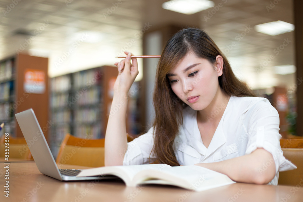 亚洲美女女学生在图书馆用笔记本电脑学习