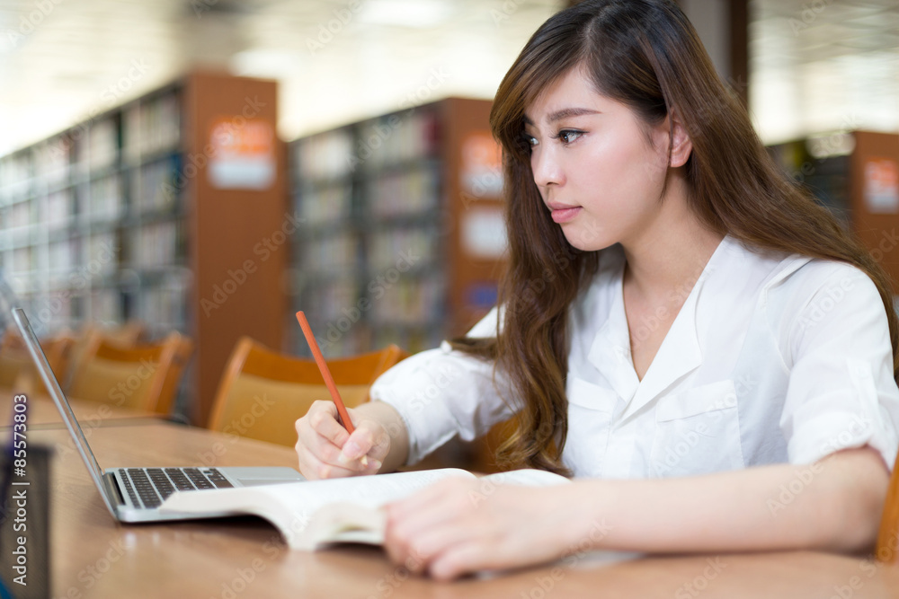 亚洲美女女学生在图书馆用笔记本电脑学习