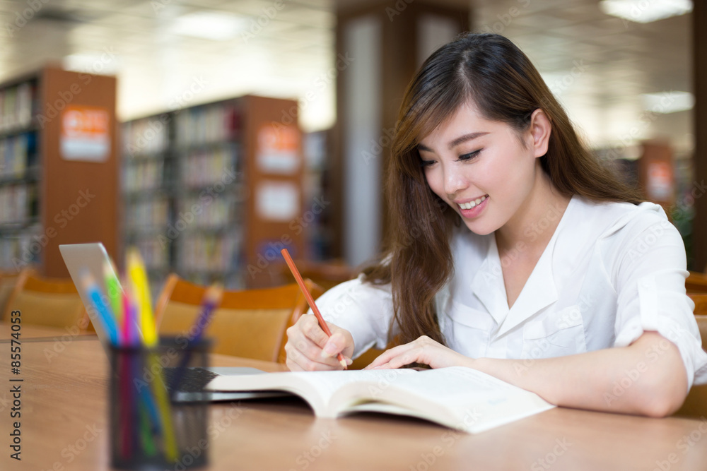 亚洲美女女学生在图书馆用笔记本电脑学习