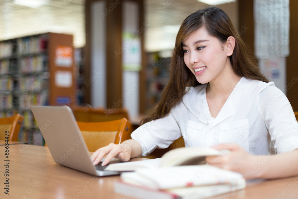 亚洲美女女学生在图书馆用笔记本电脑学习