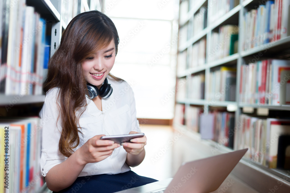 Asian beautiful female student using laptop and mobile phone in