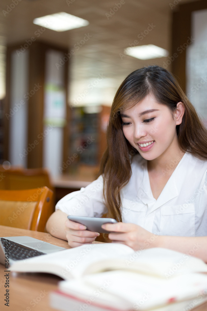 亚洲美女女学生在图书馆用笔记本电脑学习