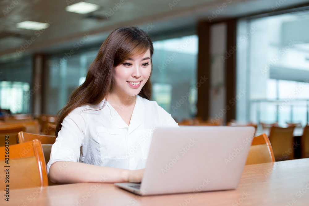 亚洲美女女学生在图书馆用笔记本电脑学习