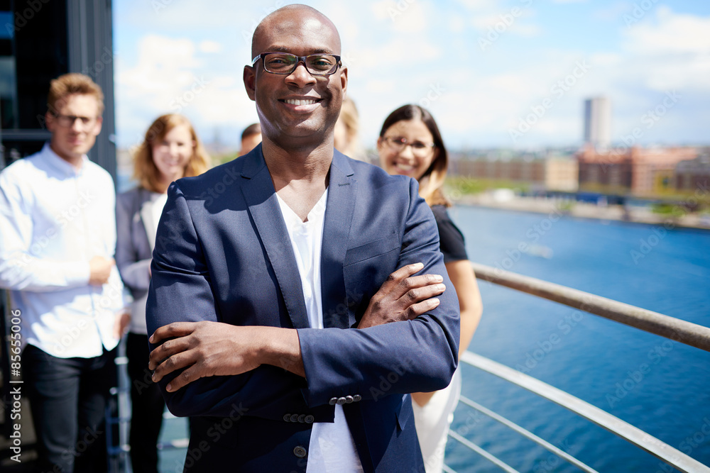 Black male executive standing in front of colleagues