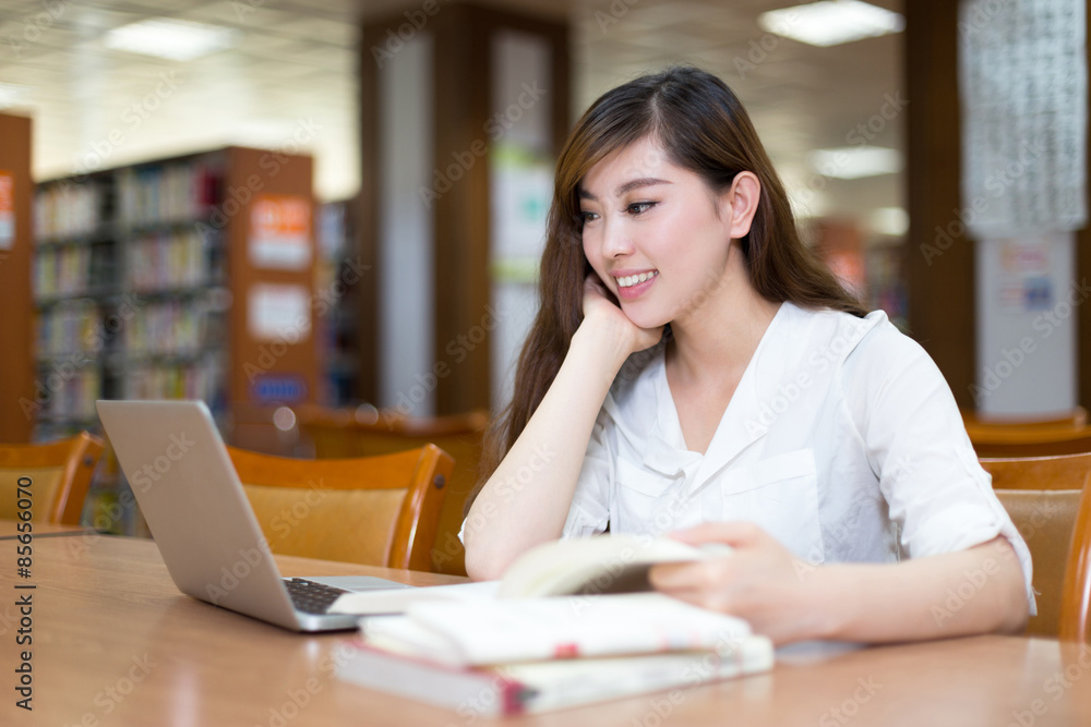 亚洲美女女学生在图书馆用笔记本电脑学习