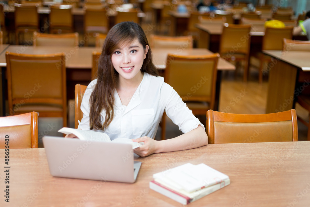 亚洲美女女学生在图书馆用笔记本电脑学习