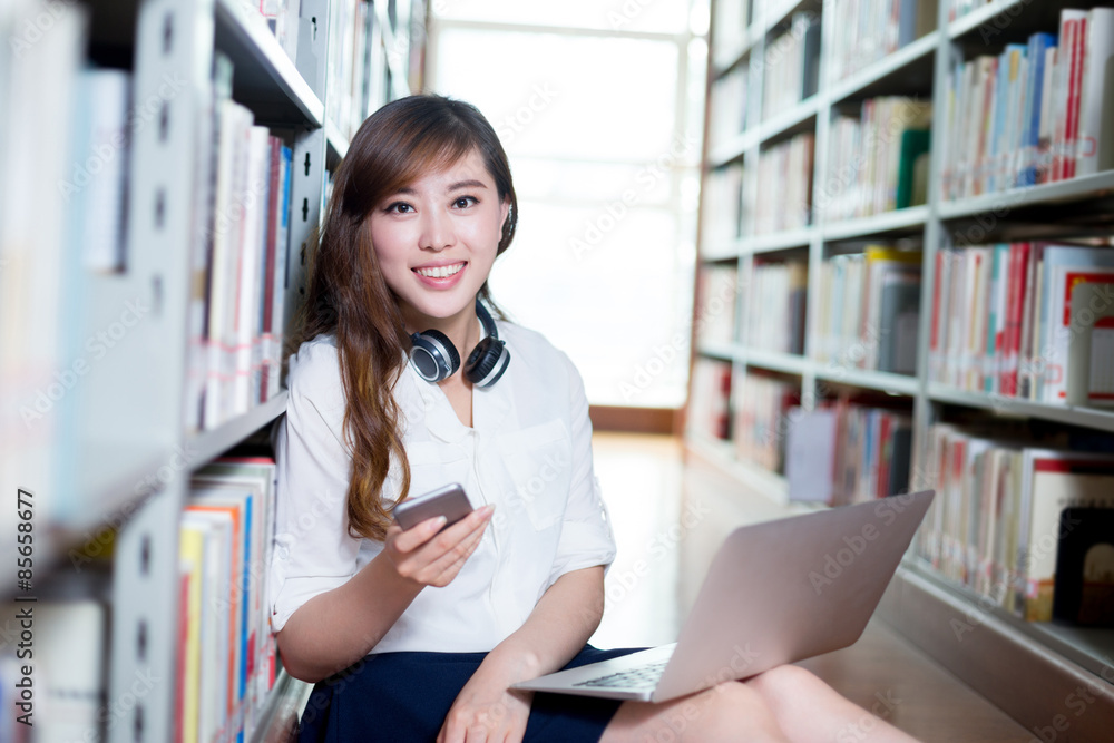 Asian beautiful female student using laptop and mobile phone in