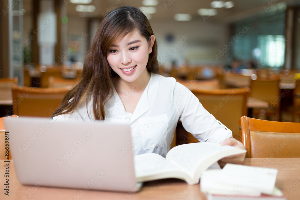 亚洲美女女学生在图书馆用笔记本电脑学习