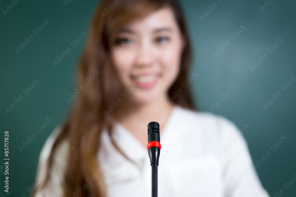 Asian beautiful woman speaking in front of blackboard with micro