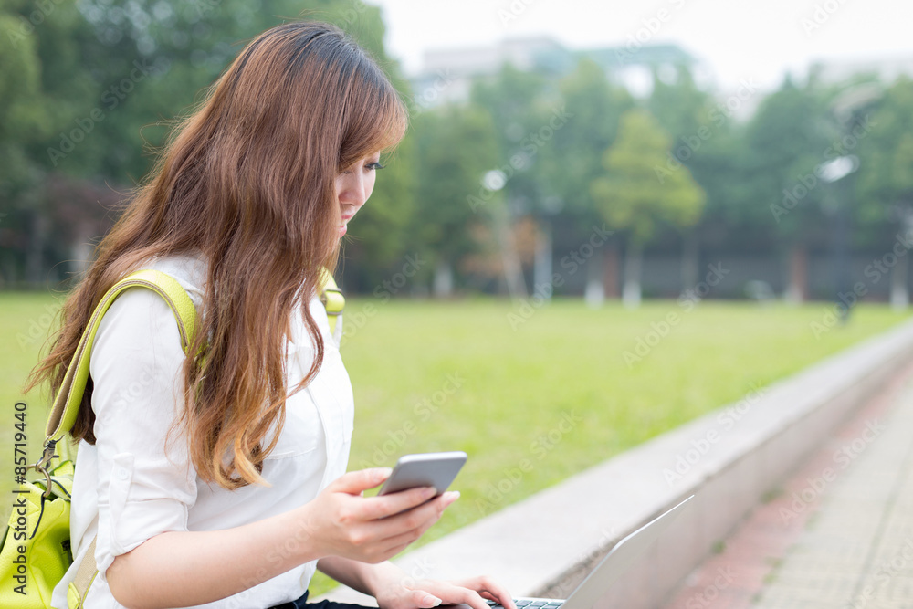 亚洲美女女学生在校园里使用手机