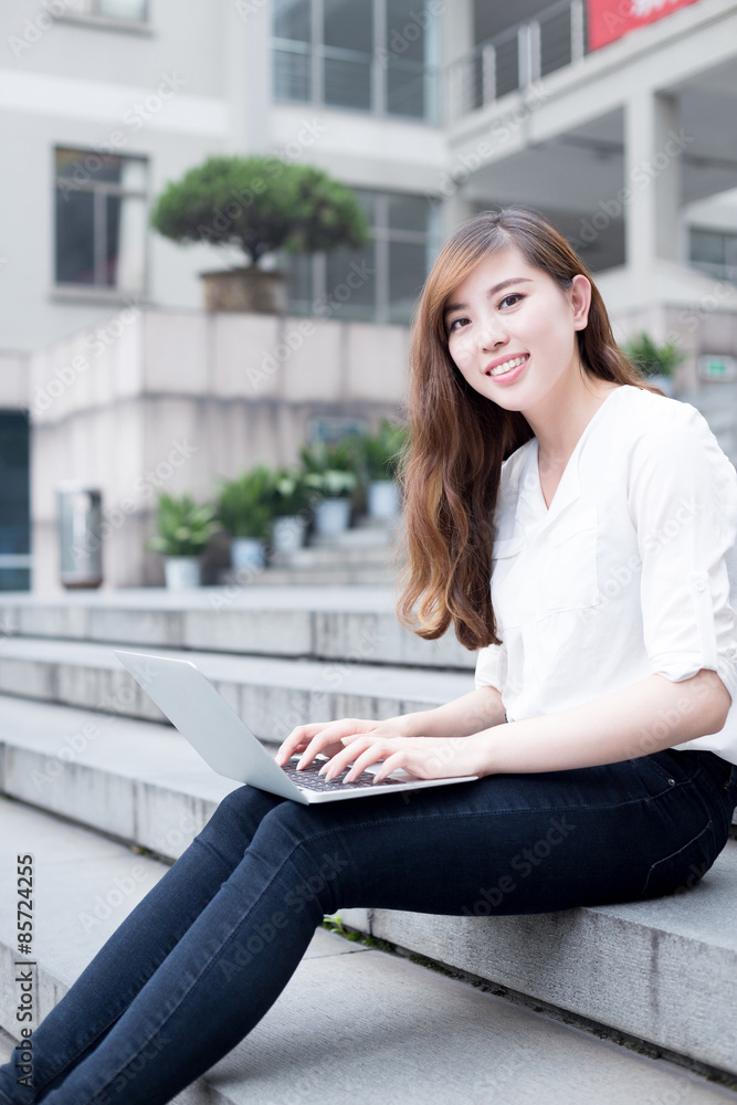 Asian beautiful female student using laptop in campus