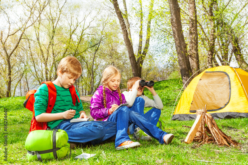 Happy children resting near the wooden bonfire