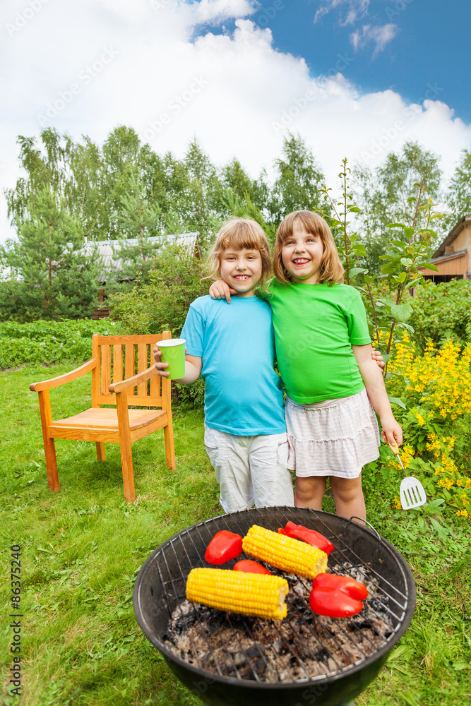 Two happy sisters stand in hug near BBQ grilling