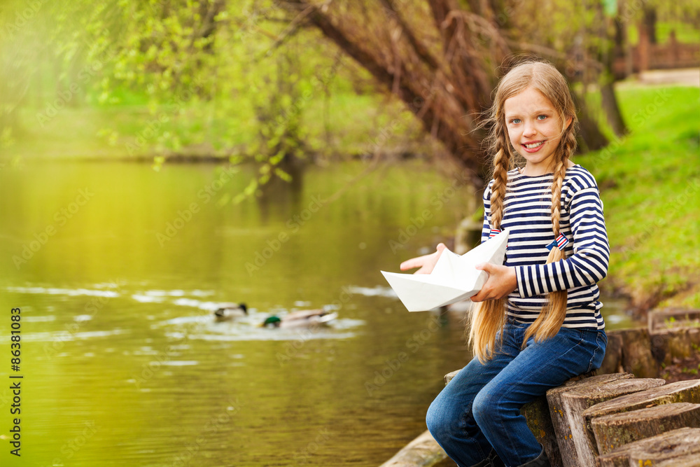 Portrait of girl near the pond holding paper boat